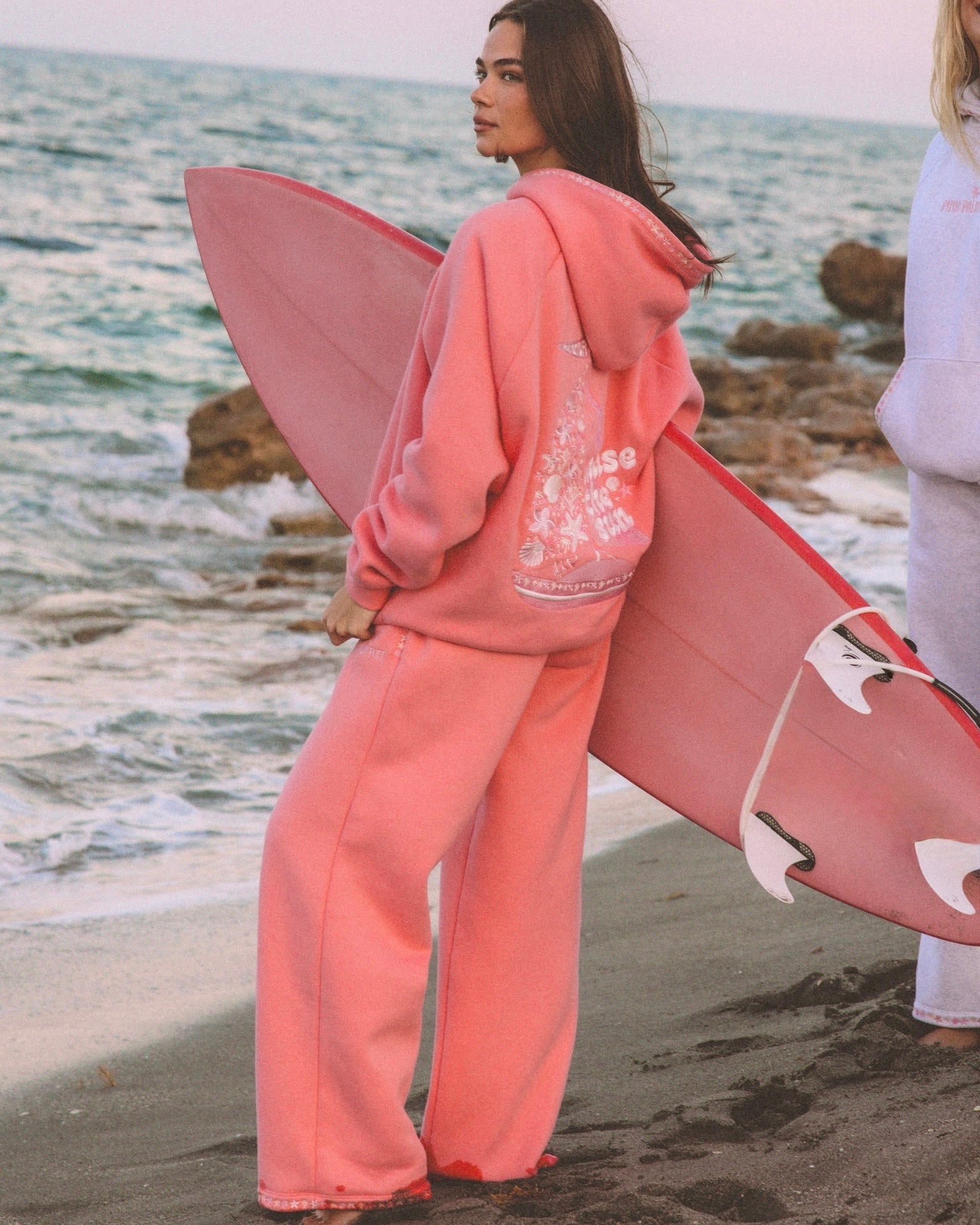matching coral pink set, with pink palm puff pattern border. girl holding surfboard, going to the beach, aesthetic beach photo